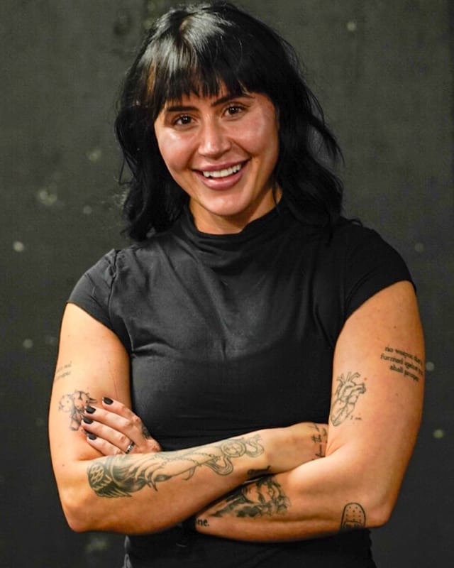 Brianna D., Denver personal trainer and nutrition coach at PHNX Fitness, smiling with arms crossed