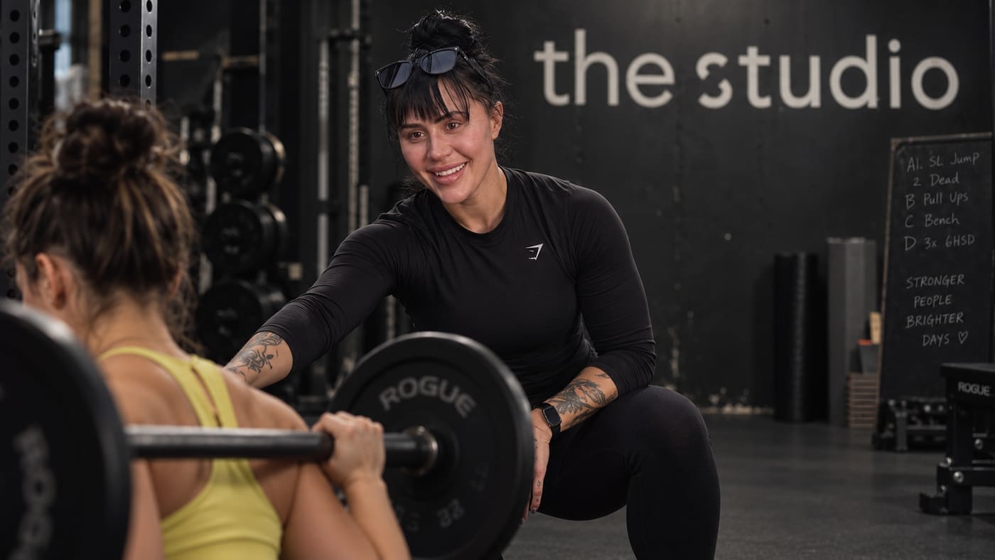 Personal trainer Brianna guiding a client through a barbell squat at a private studio in Cherry Creek, Denver